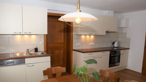 Eine moderne Küche mit weißen Schränken, einer Holz Arbeitsplatte, einem eingebauten Ofen und einem Esstisch mit Stühlen.