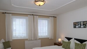 Ein Schlafzimmer mit zwei Betten, Holzboden, Heizkörper und einem an der Wand befestigten Bilderrahmen.
