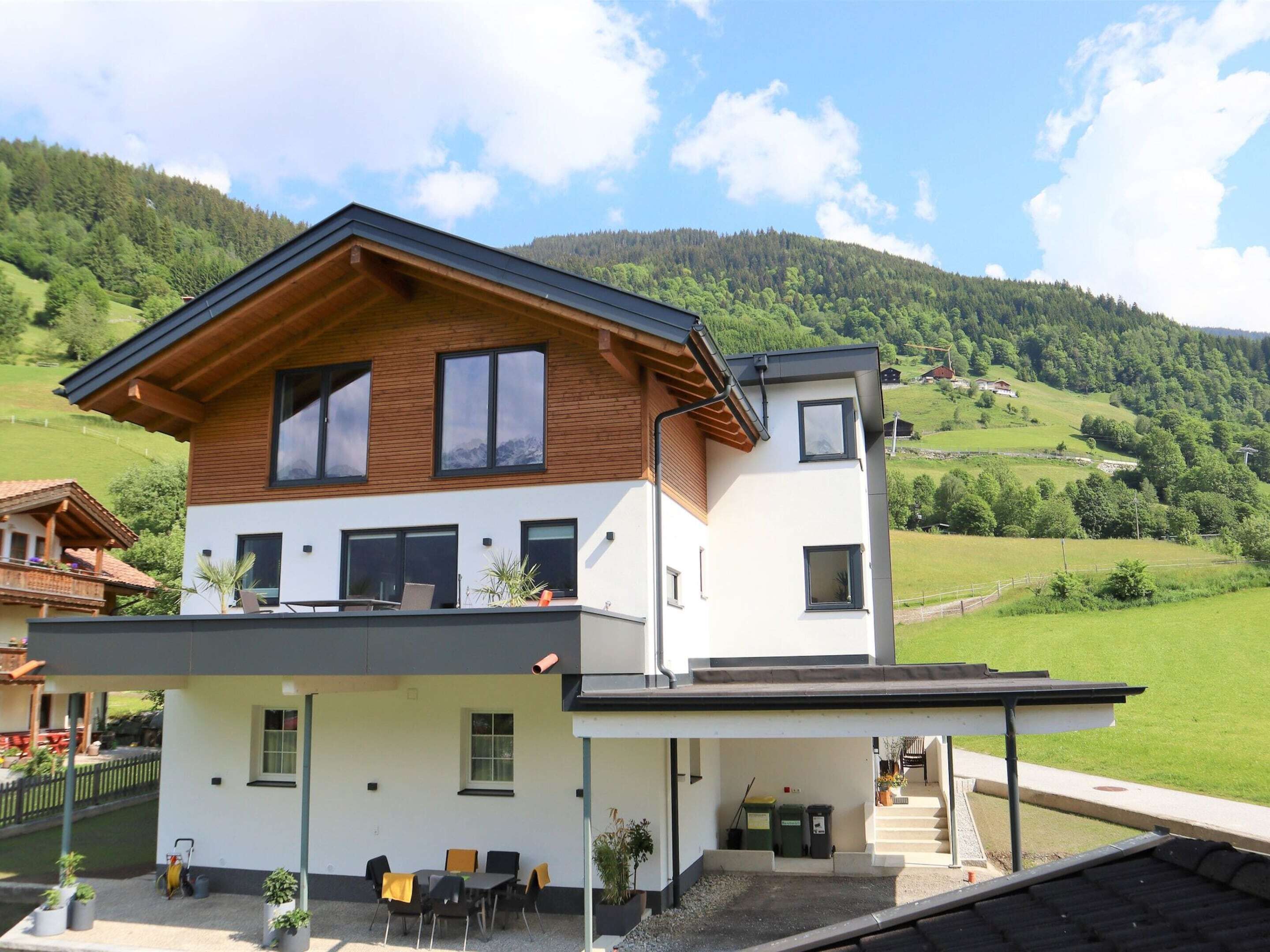 A two-story modern house with a wooden roof, white walls, and a balcony.