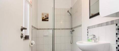 A bathroom with a toilet, shower, and sink.