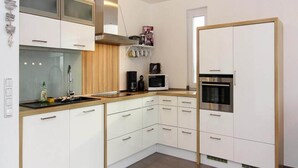 A modern kitchen with white cabinets, a microwave, a stove, and a built-in oven. - Ferienhaus de Poeler Drift, Zierow (Zierow)