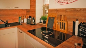 A modern kitchen with a black stovetop, wooden cabinets, and a wall-mounted sign reading "Sternküche". - Ferienwohnung in Bodenmais am Grossen Arber (Bodenmais)