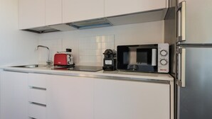 Eine moderne Küche mit weißen Schränken, einem Edelstahlkühlschrank, einem roten Toaster und einer schwarzen Mikrowelle.