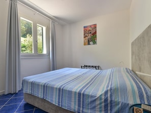 A bedroom with a bed, a window, a painting, and a chair. - Apartment in Elba Near Straccoligno Beach (Capoliveri)