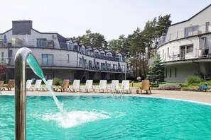 Una piscina amb una font, envoltada de gandules i un edifici amb balcons.