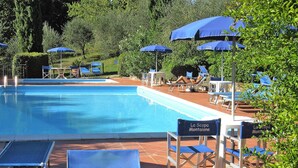 Ett poolområde med blå parasoller, solstolar och en skylt med texten ”La Scopa Montagna”.