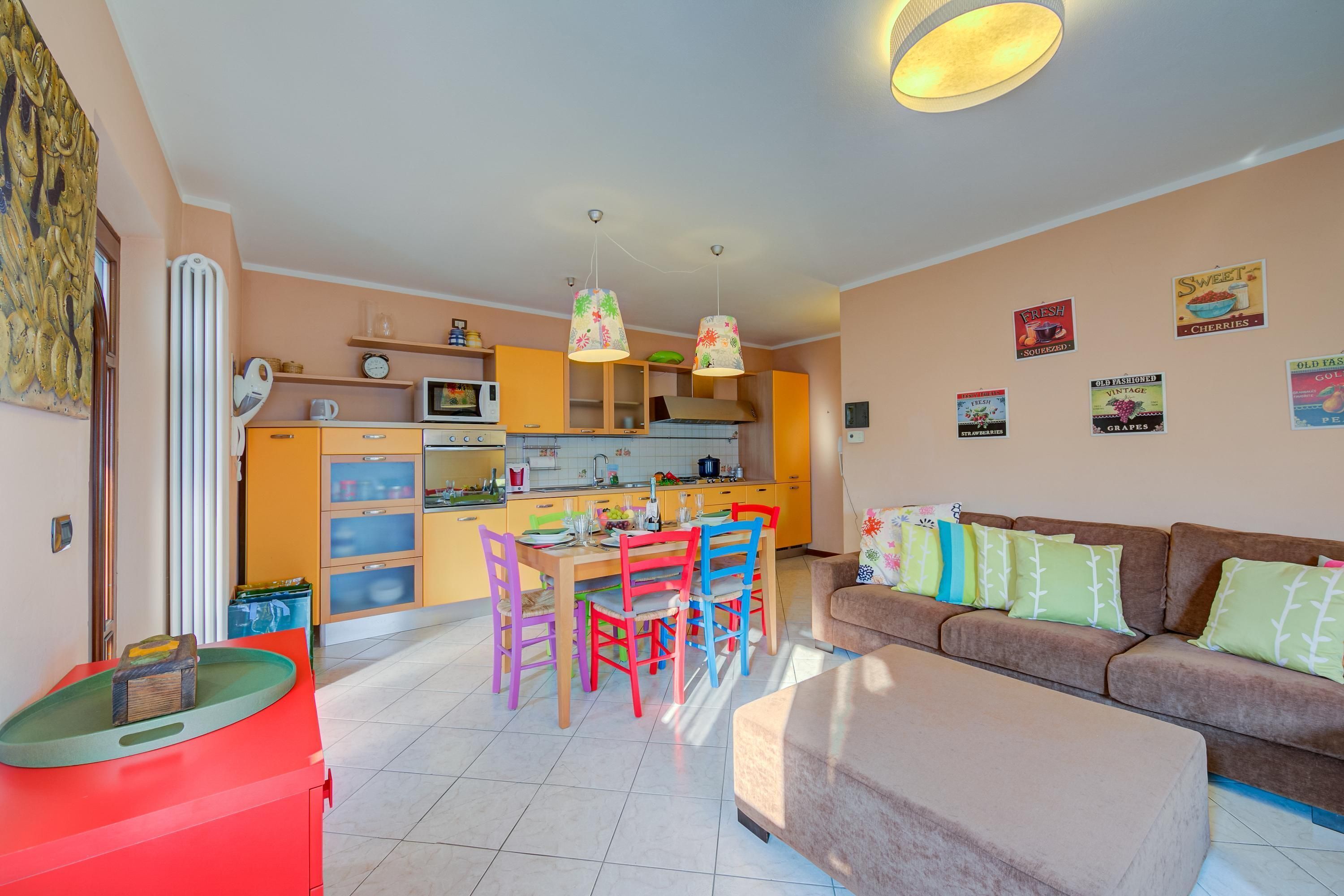 A modern kitchen with a dining area, a sofa, and a red cabinet.