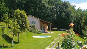 A house with a swimming pool, surrounded by a well-maintained lawn and garden. - Apartment in Tuscany With Pool & Golf Access (Gambassi Terme)