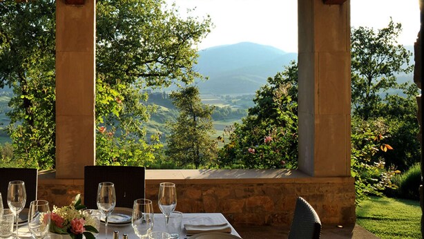 An outdoor dining area with a table set for two, overlooking a scenic landscape with mountains and greenery. - Apartment in Tuscany With Pool & Golf Access (Gambassi Terme)