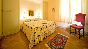A bedroom with a double bed, a chair, a rug, and a painting on the wall. - Apartment in Tuscany With Pool & Golf Access (Gambassi Terme)