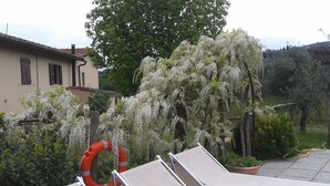 A rooftop with white lounge chairs, a red lifebuoy, and a tree with white flowers. - Romantic studio apartment with a view (Toscana)
