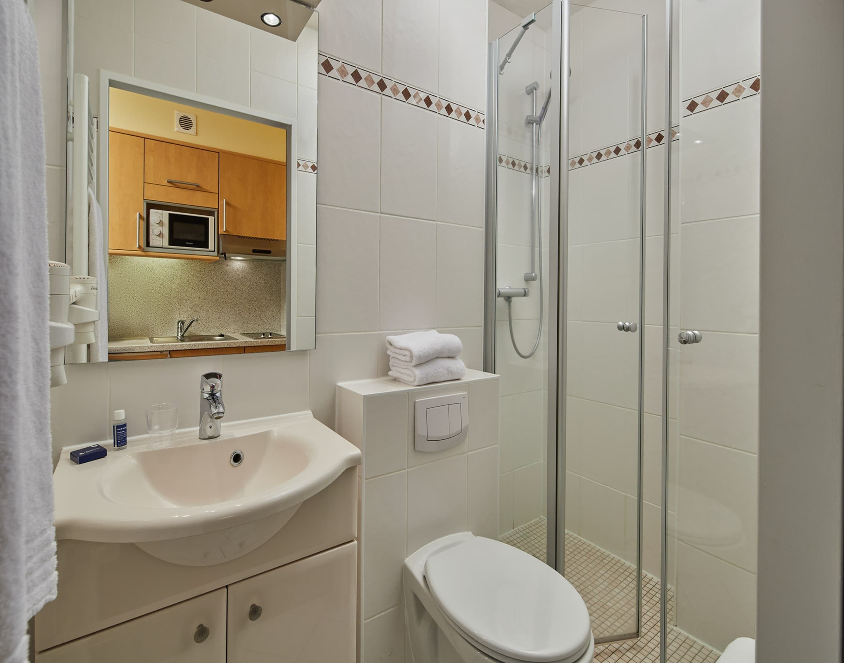 A modern bathroom with a sink, toilet, and glass shower enclosure.