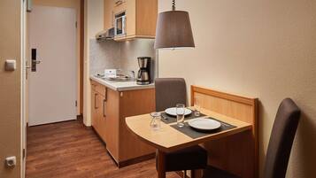 Una kitchenette compacta equipada con microondas, cafetera y una lámpara colgante.