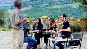 Un groupe de personnes est assis à une table en plein air, avec une vue panoramique sur des collines en arrière-plan.