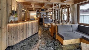 Un interior de madera con mostrador de recepción, zona de estar y chimenea.