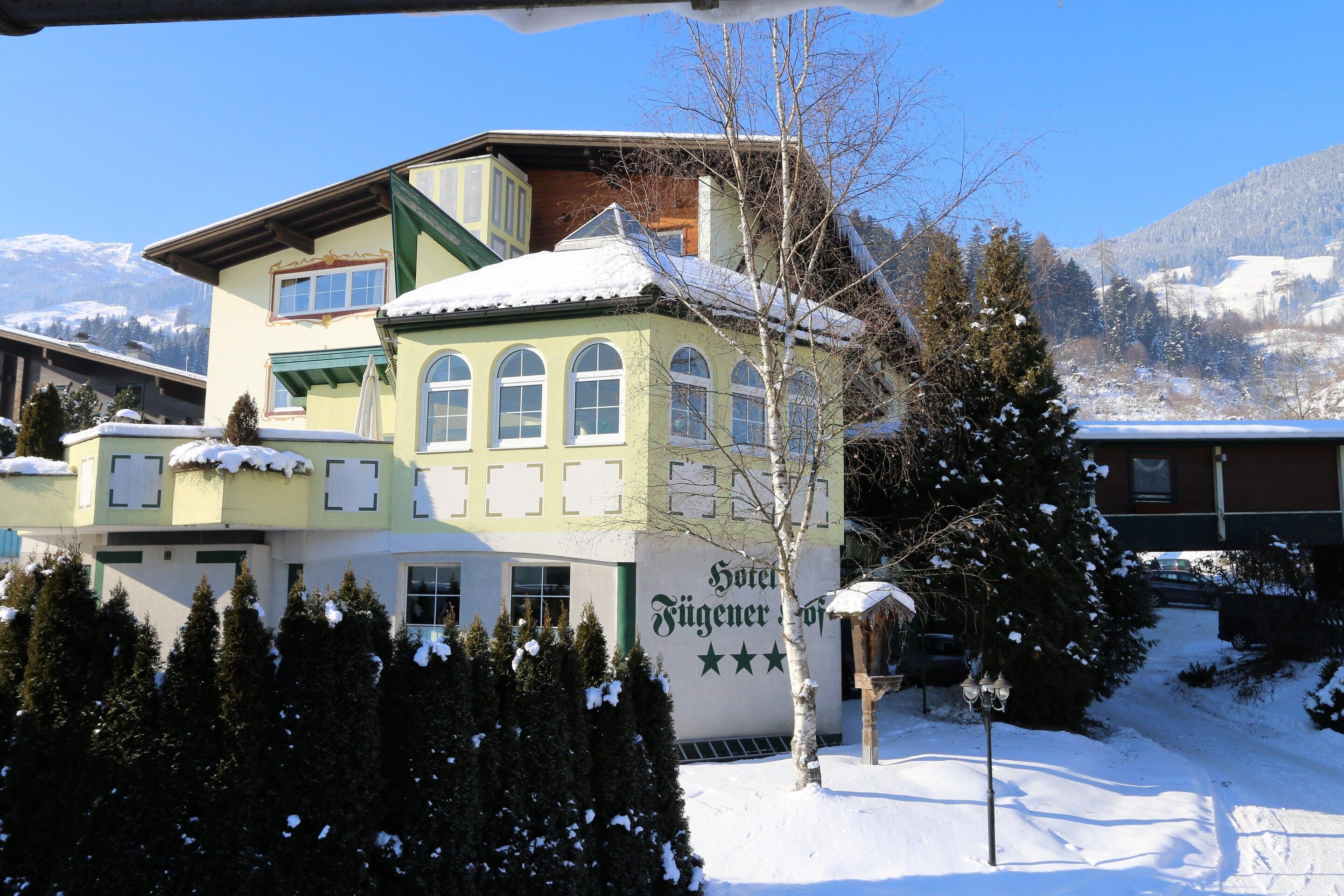 A hotel with a snow-covered roof and a mountain view.