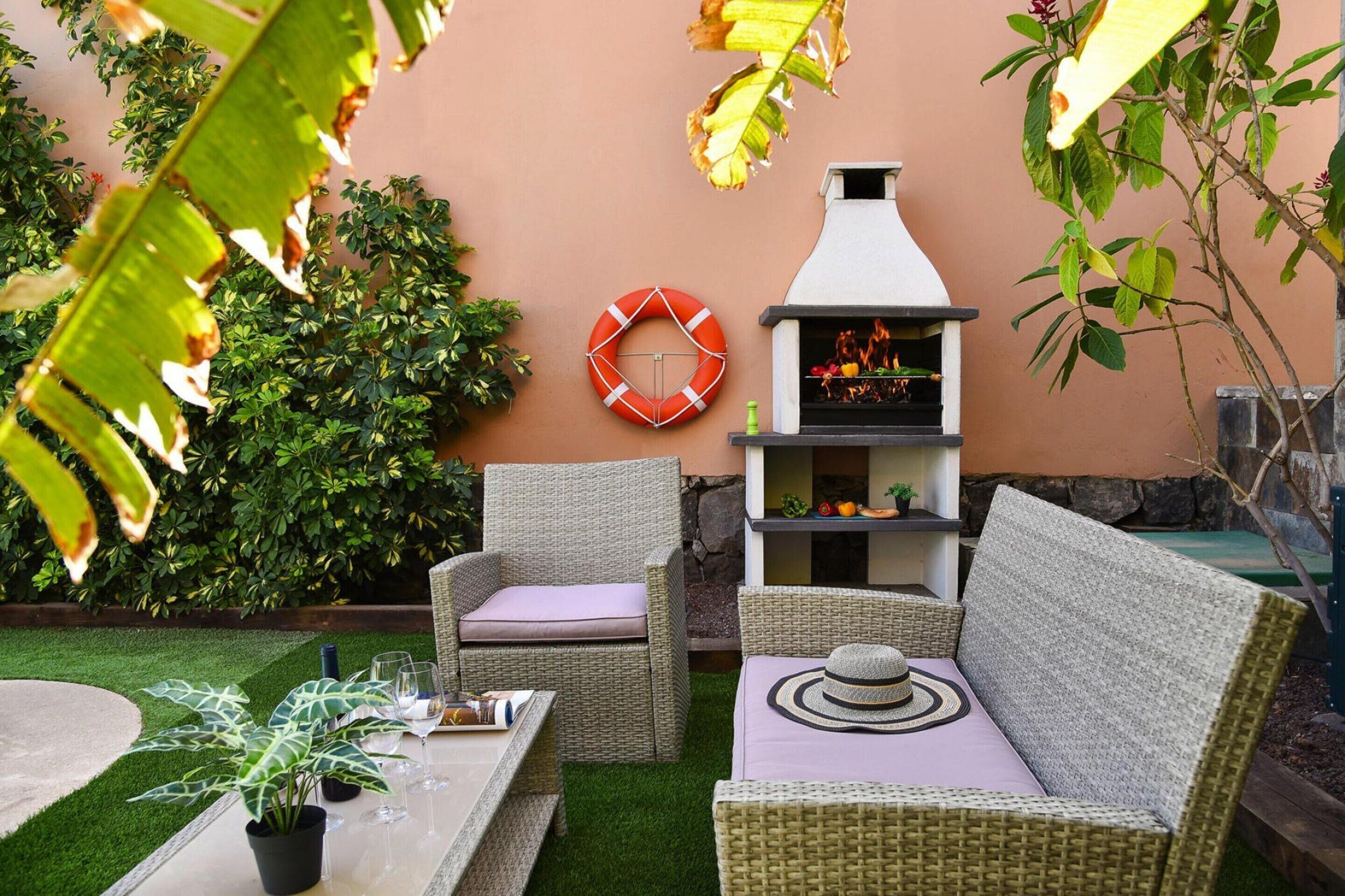 Un espace extérieur aménagé avec des meubles en osier, un barbecue et une décoration murale représentant un dispositif de sauvetage.