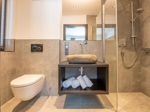 A modern bathroom with a toilet, a sink with a stone basin, and a shower. - Chalet in Wald Near Krimml Waterfalls (Wald im Pinzgau)