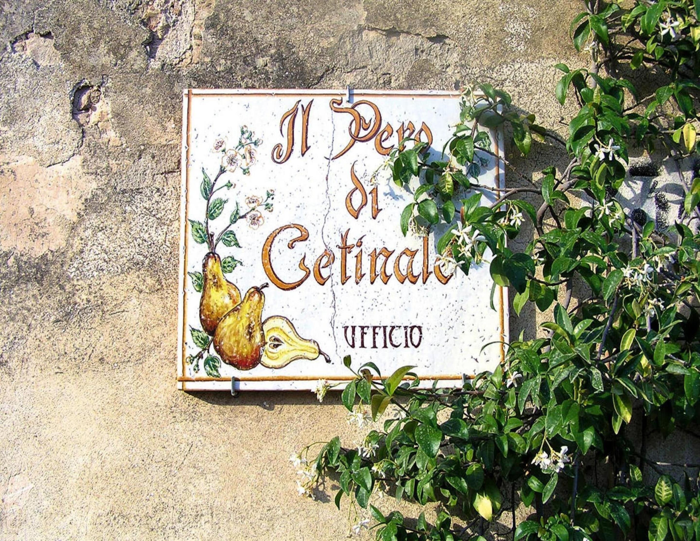A sign with the text "Il Pesco di Cetralia" and "UFFICIO" on a stone wall.