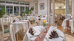 Un espace repas avec des tables rondes, des chaises et des nappes blanches. Des plantes et des bougies sont disposées sur les tables.