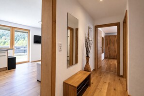 A modern interior with a wooden floor, a bench, a mirror, and a vase with branches. - Holiday Home in Aschau by Zillertal Alps (Aschau Im Zillertal)