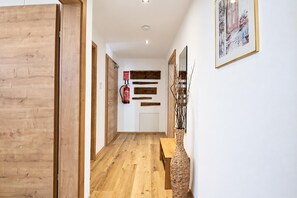 Un couloir doté d’un plancher en bois, d’un extincteur fixé au mur et d’un tableau encadré accroché au mur.