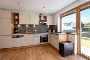 Een moderne keuken met inbouwapparatuur, een vaatwasser en een raam met uitzicht op een woonwijk.