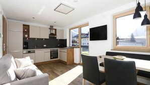 Une cuisine moderne avec un coin repas, un canapé et un téléviseur fixé au mur.