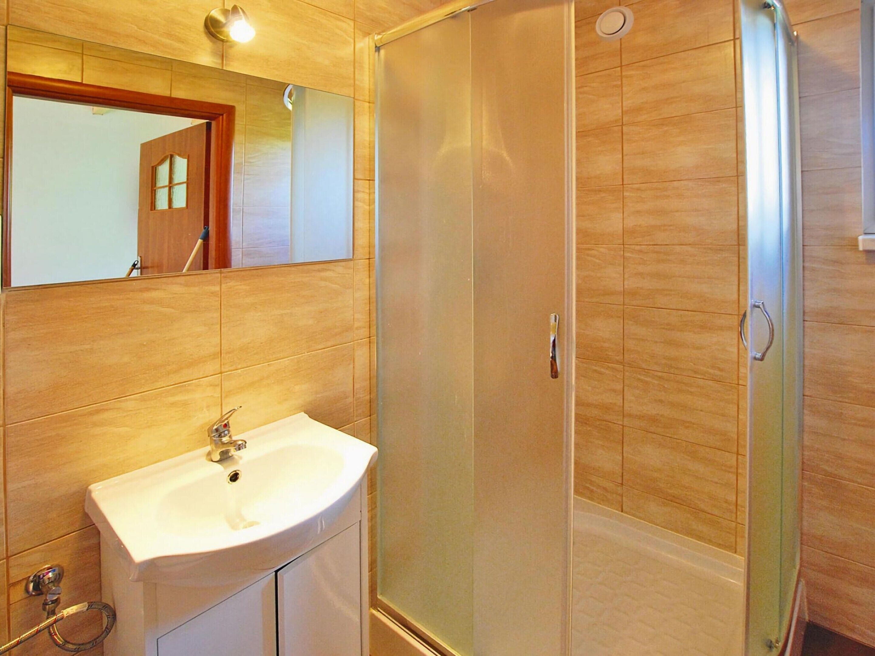 A bathroom with a white sink, a mirror, and a glass-enclosed shower.