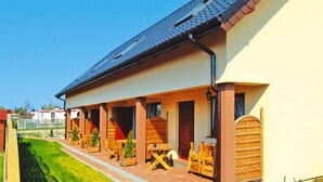 Een gebouw met een overdekte veranda, houten meubilair en een dak voorzien van zonnepanelen.