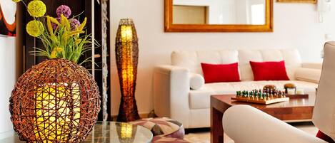 A living room with a white sofa, red cushions, a glass coffee table, and a chessboard.