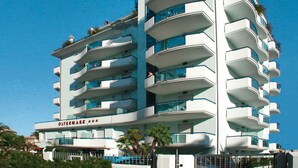 Ein mehrstöckiges Hotel mit Balkonen, blauem Himmel und Palmen.