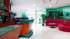 Eine moderne Bar mit Marmorplatte, roten Sitzgelegenheiten und Topfpflanzen.