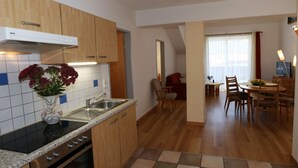 A modern kitchen with wooden cabinets, a built-in oven, and a tiled backsplash. - Apartment in Bichlbach Near Zugspitze (Bichlbach)