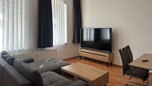 A modern living room with a sofa, a coffee table, a TV, and a dining table with chairs. - Ferienwohnung im Zentrum von Ballenstedt (Ballenstedt)