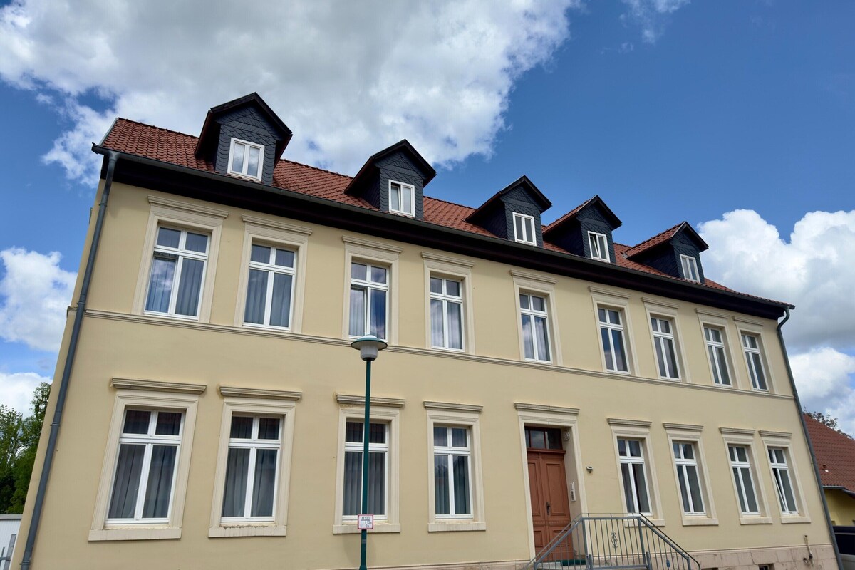 Un immeuble à plusieurs étages, doté d’une façade symétrique, de nombreuses fenêtres et d’une entrée centrale avec une porte.