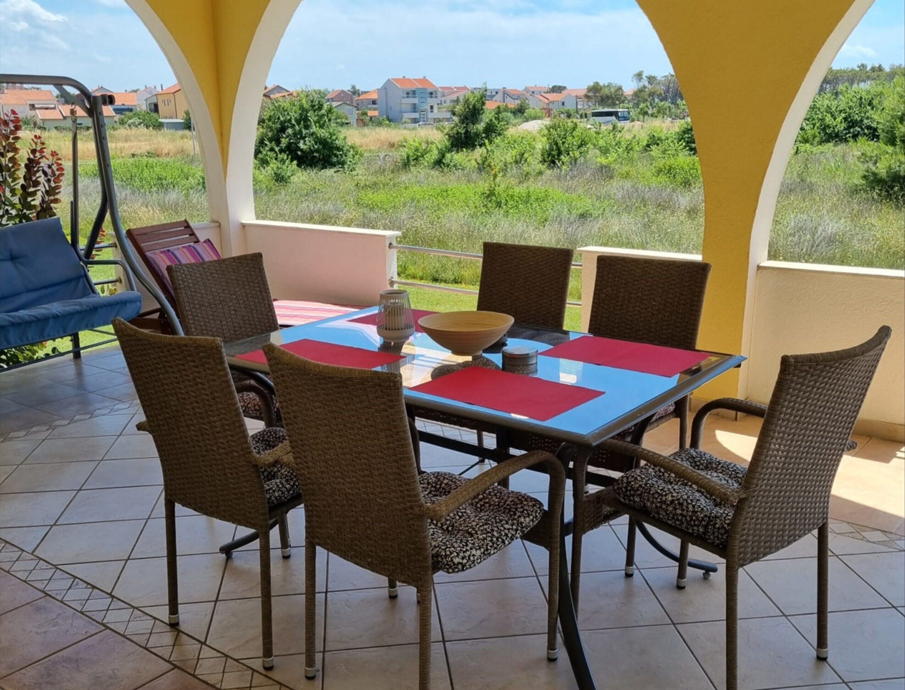 Un'area pranzo all'aperto riparata, con tavolo, sedie, una ciotola e una candela.