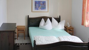 Une chambre à coucher avec un lit, une table de chevet en bois, un bureau et un tableau encadré au mur.