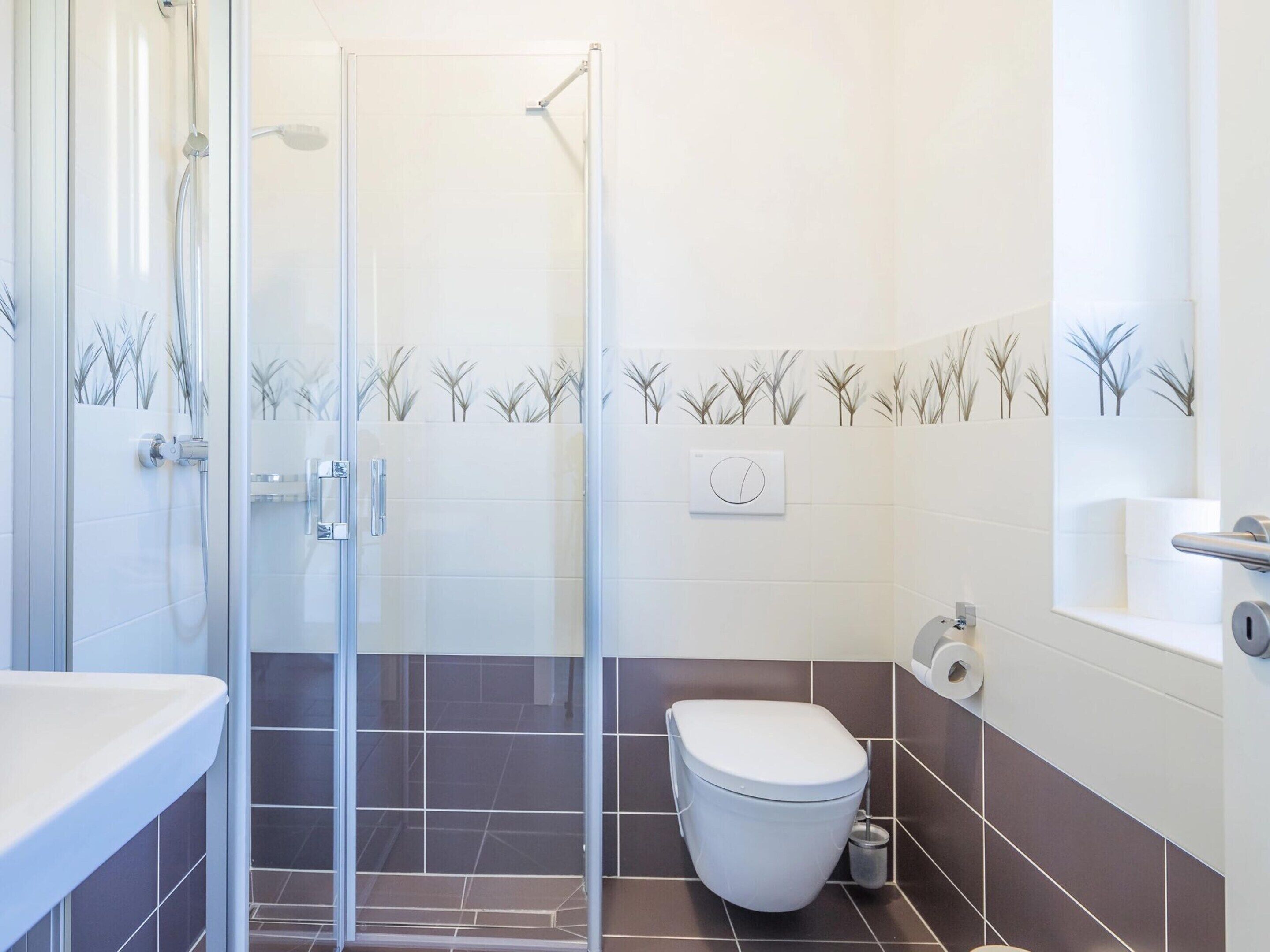 A modern bathroom with a glass shower enclosure, a toilet, and a sink.