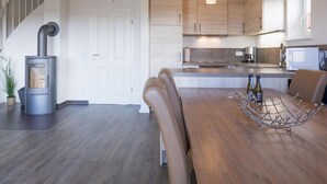 Eine moderne Küche mit Holzausstattung, einer eingebauten Mikrowelle und einem Essbereich mit Holztisch und Ledersesseln.