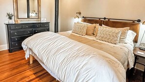 Une chambre à coucher avec un grand lit, une commode, un miroir et un ventilateur de plafond.