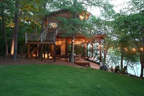 Eine Holzhütte mit einer Terrasse, Sitzgelegenheiten im Freien und Lichterketten.