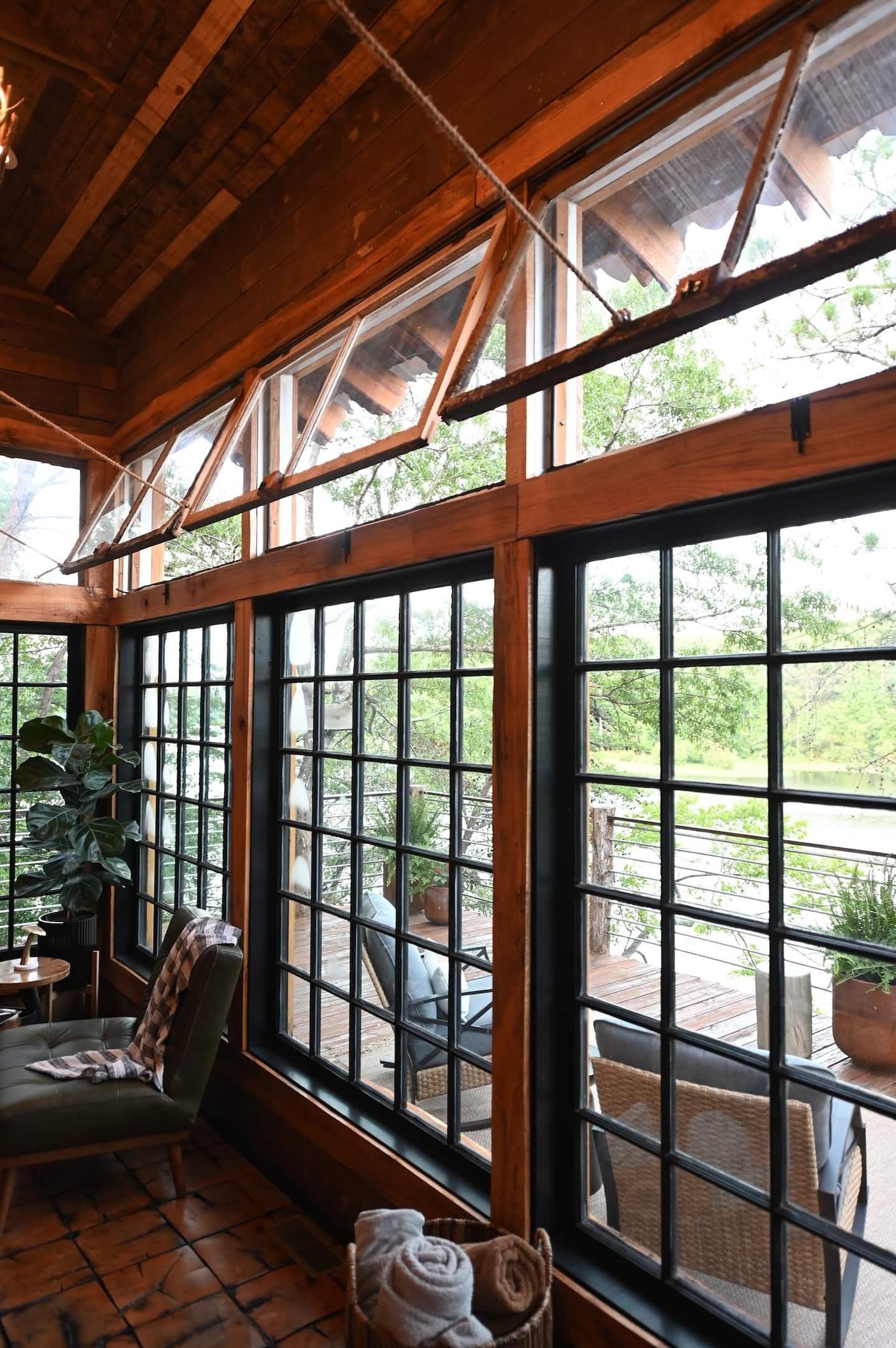 Una habitación con amplios ventanales, vigas de madera y vistas al exterior.