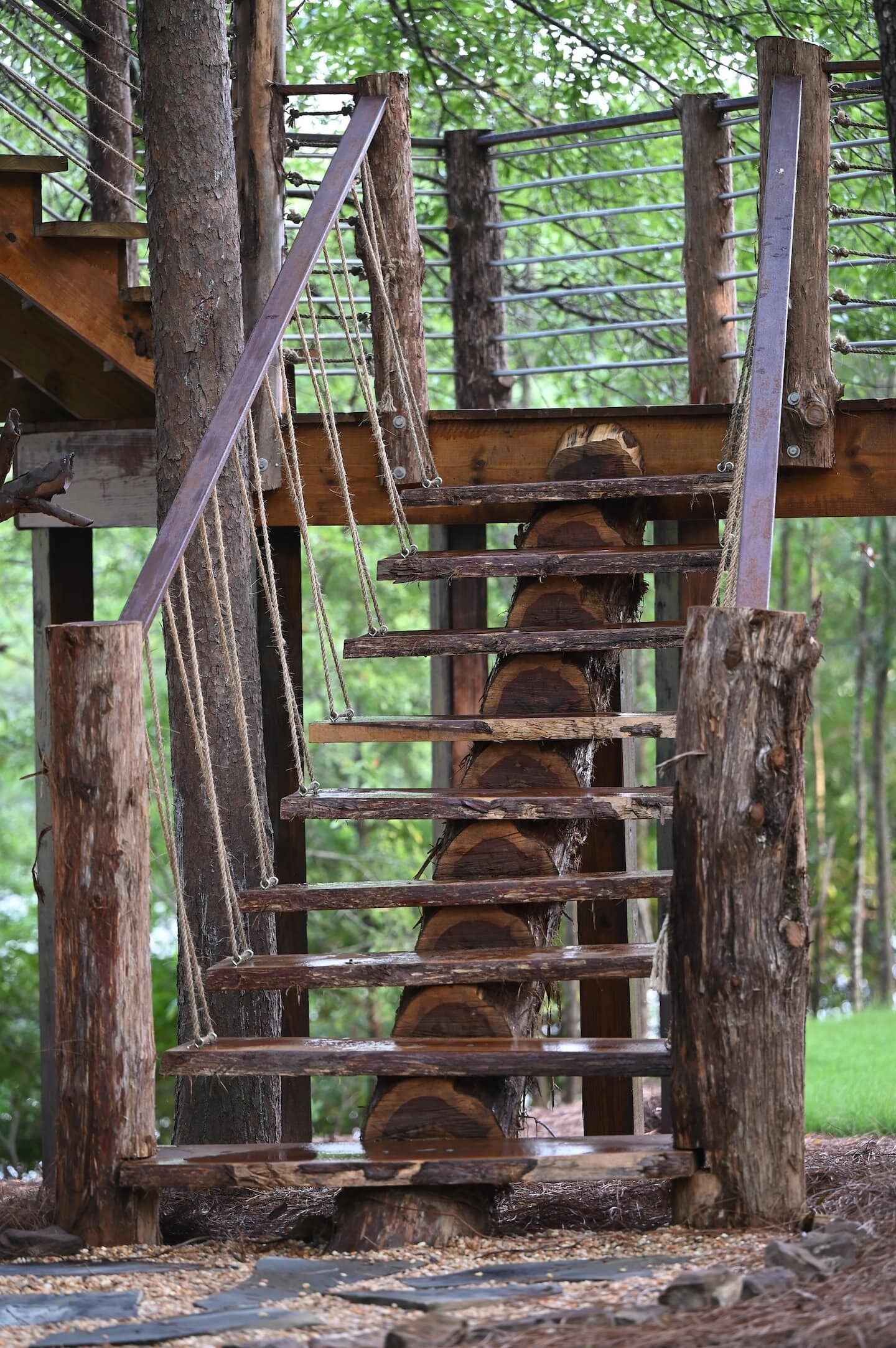 A wooden staircase with a metal handrail leading up to a platform.