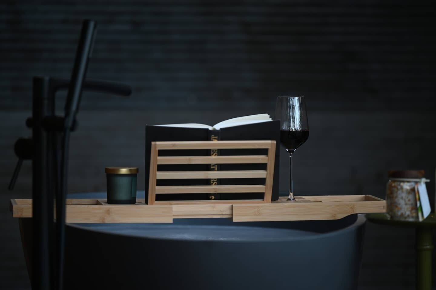 Una mesa con un libro, una copa de vino y una vela.