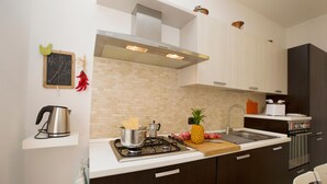 A modern kitchen with a gas stove, a stainless steel kettle, a toaster, and a microwave.