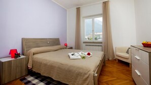 A neatly arranged bedroom with a bed, bedside tables, a dresser, and a window with a view.