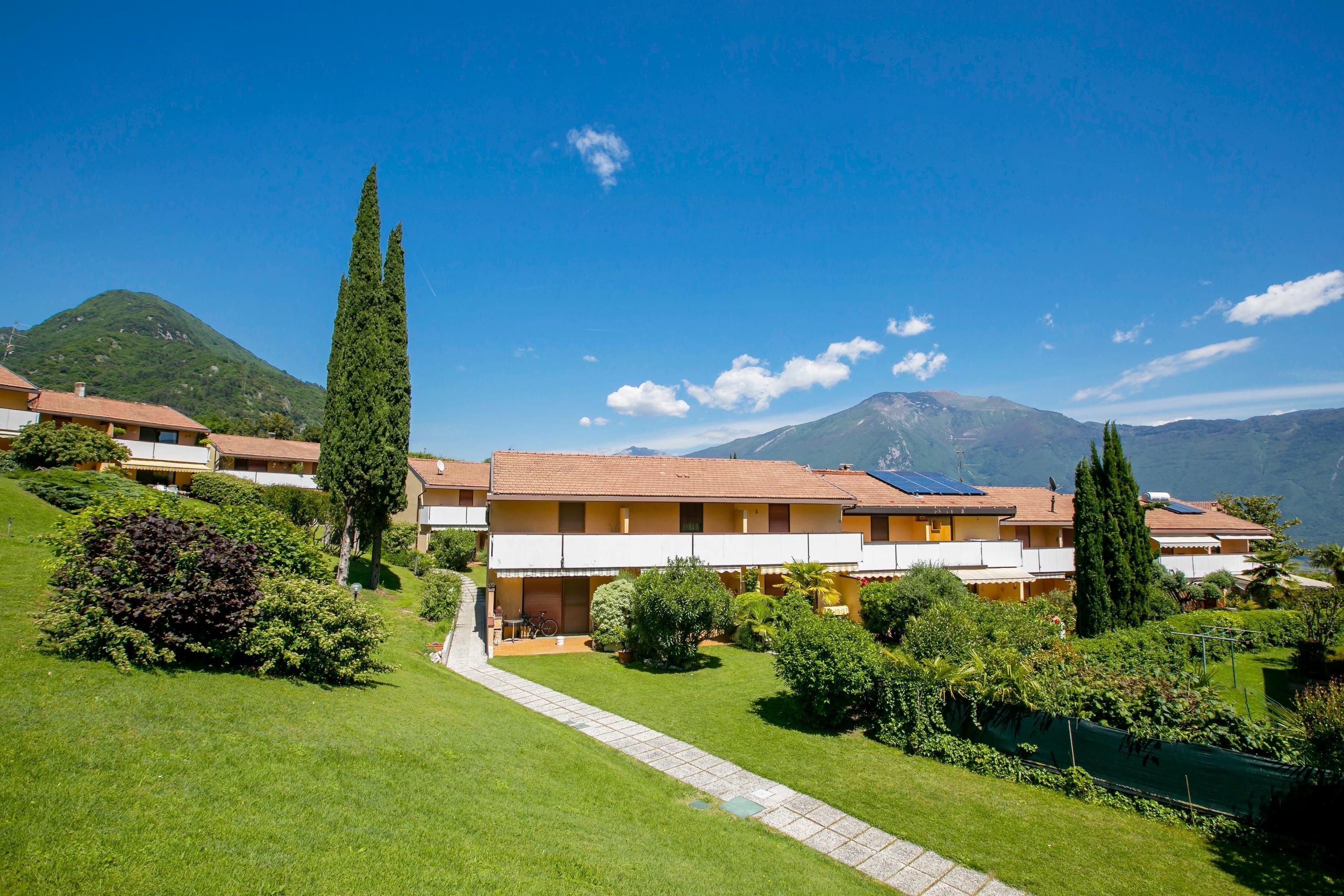 Un hôtel situé sur une colline, composé de plusieurs bâtiments, avec un sentier et entouré de verdure.