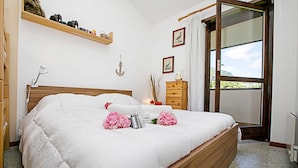 A neatly made bed with a wooden headboard, a bedside table with a lamp, and a window with a view of greenery. - Residence Christina Due Laghi (Tenno)