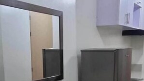 Eine kleine Küche mit Holztisch und Stühlen, einem Kühlschrank und Schränken.